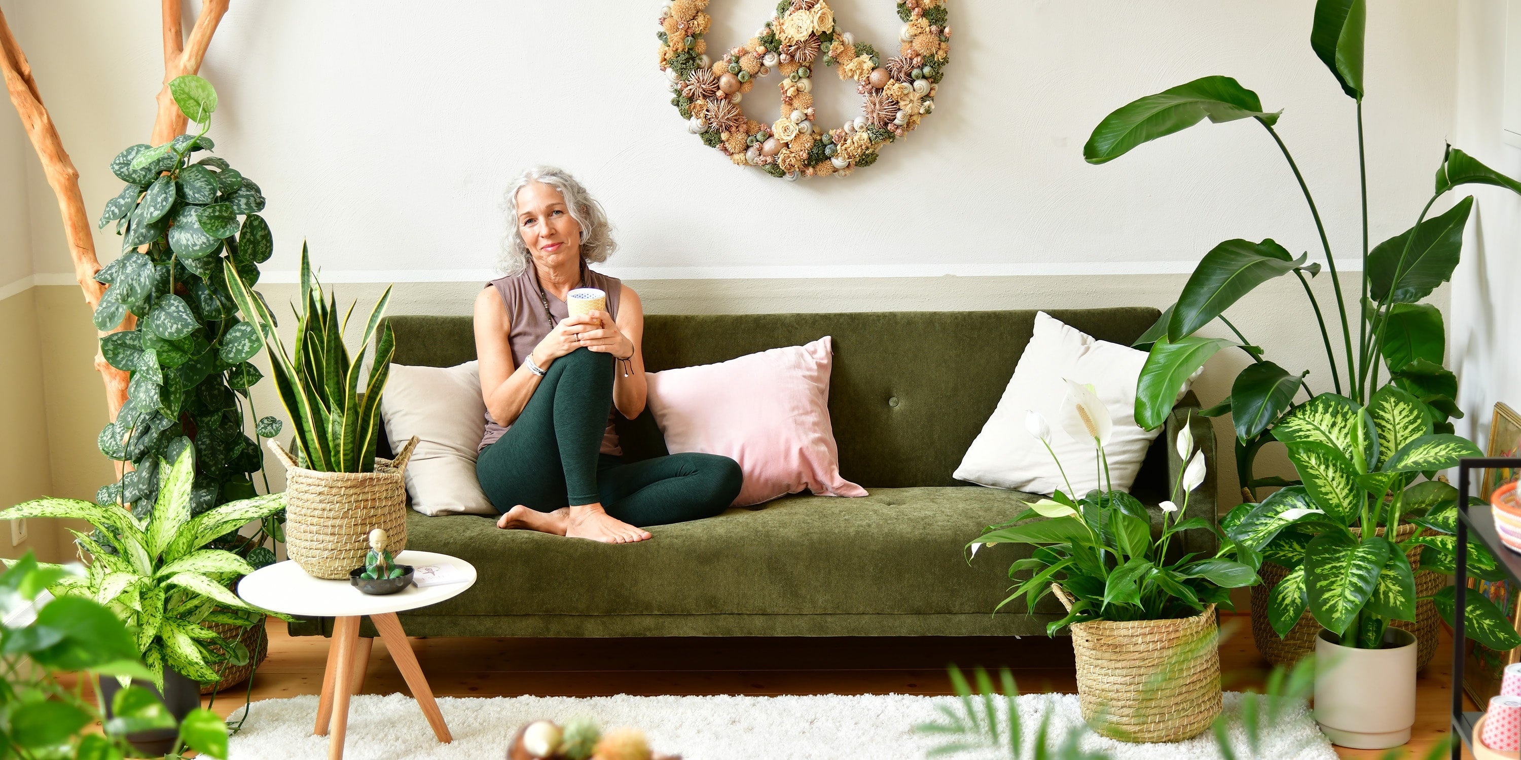 Yoga Frau sitzt auf Couch mit Pflanzen 