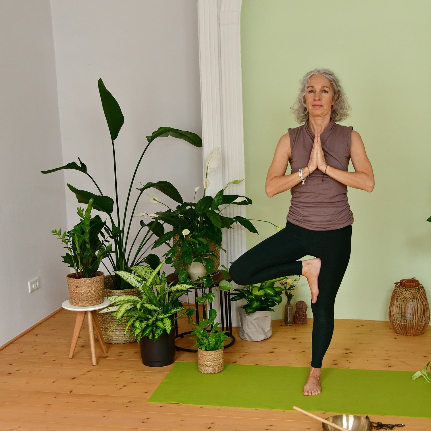 Frau macht Yoga Übung neben Pflanzen