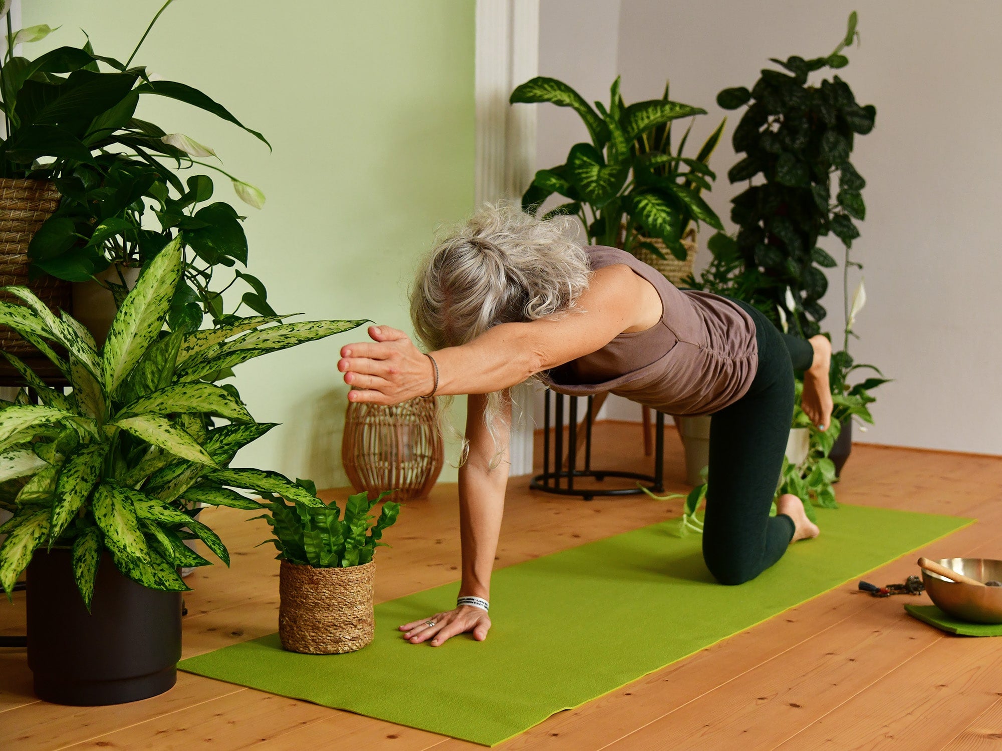 Frau macht Yoga Übungen zwischen Pflanzen