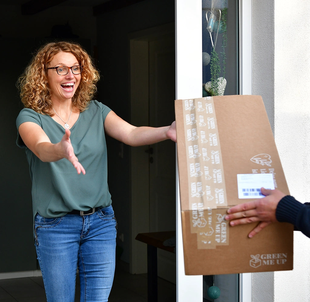 Frau nimmt mit strahlendem Gesicht ihr Paket mit Pflanzen an