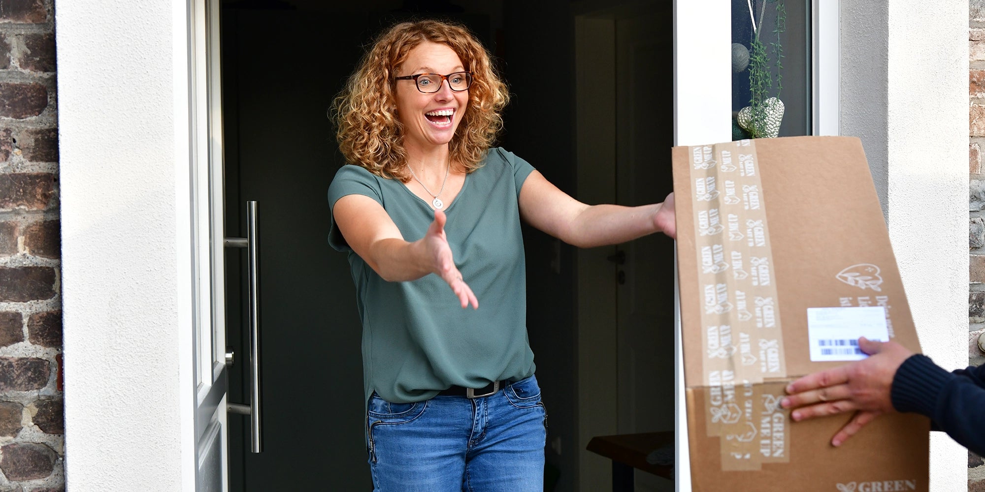 Frau nimmt Paket mit Pflanzen für den Balkon an und freut sich sehr